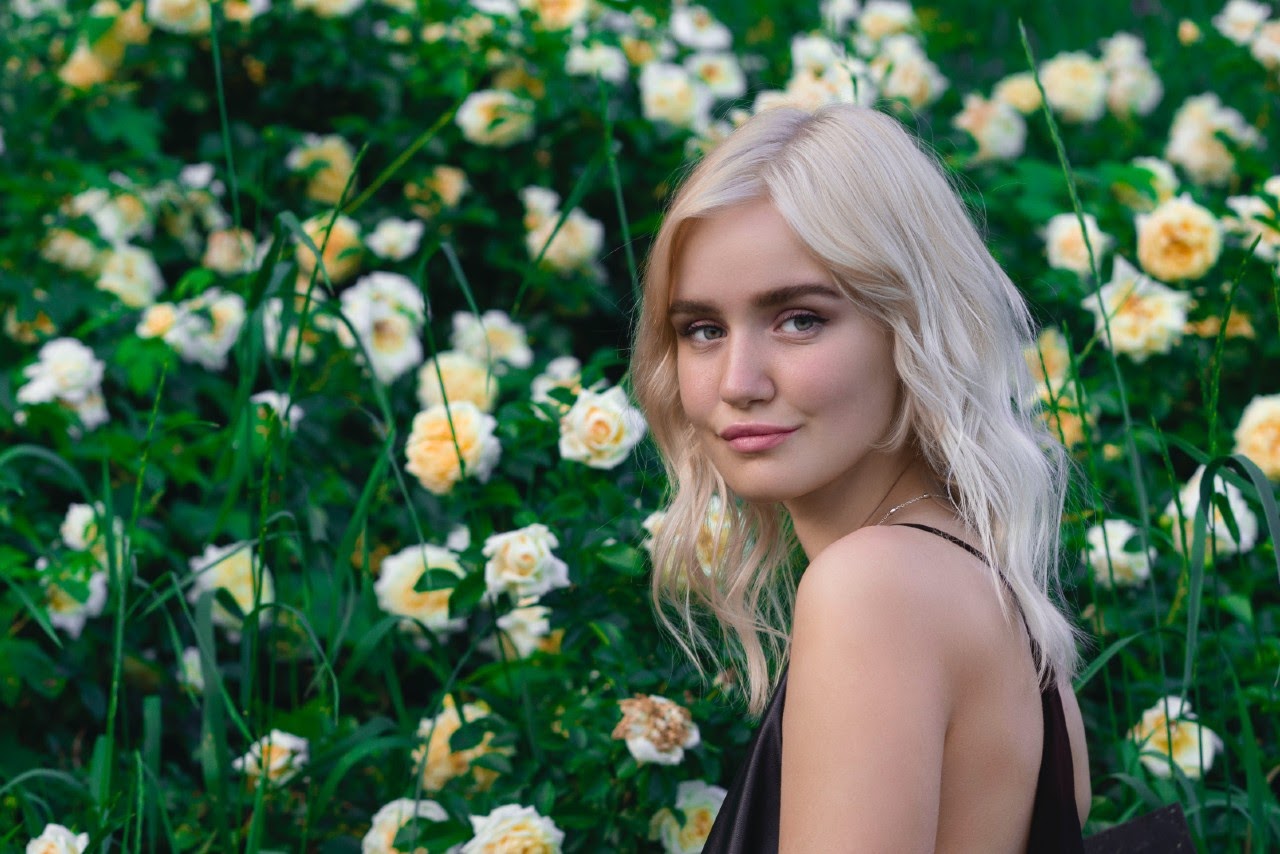 Woman in-front of the rose garden with smiling face